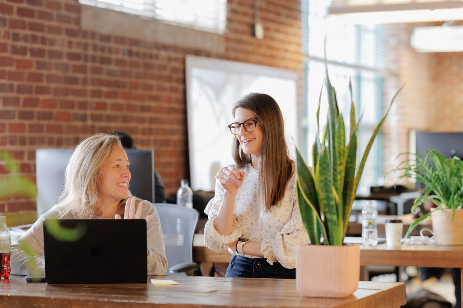 CloudConnex team members collaborating in a bright, modern workspace with natural light and open design